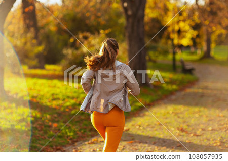 Seen from behind modern woman in fitness clothes in park jogging 108057935