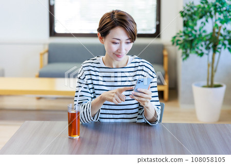 一位女士在咖啡館操作智慧型手機 一位女士在咖啡館操作智慧型手機 108058105