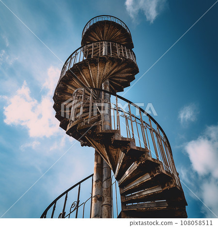Stairway to Heaven. A spiral spiral antique metal staircase goes high up into the blue sky. 108058511