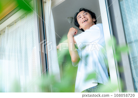 A man who opens a curtain 108058720