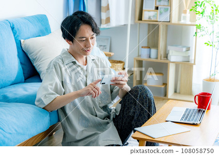 一個在客廳裡使用智能手機的人 一個在客廳裡使用智能手機的人 108058750