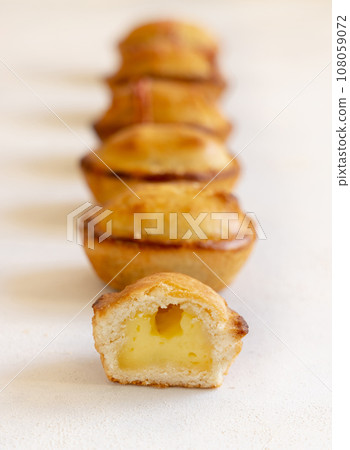 Pasticciotto leccese pastries filled with egg custard cream on a white table in a line, close up 108059072