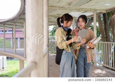 Two college student female friends smile ready for class at the university campus 108060143