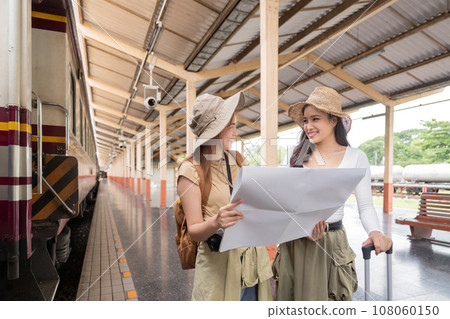 Travel concept. girl friend wear hat holding map have bag and luggage. female traveller waiting train at train station 108060150