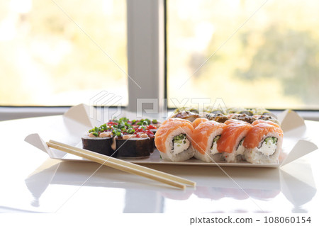 Sushi rolls in disposable paper box on table Sushi rolls in disposable paper box on table 108060154
