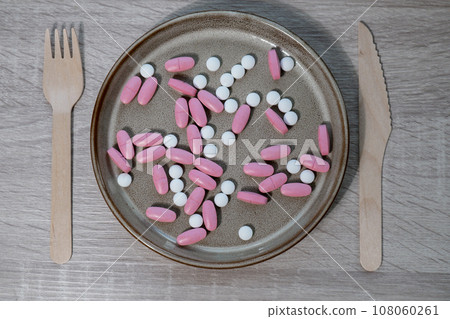 Organizer weekly shots with fork and knife medical pill box with doses of tablets for daily take medicine with white pink drugs and capsules. Daily vitamins at home. Health care and diseases cure 108060261
