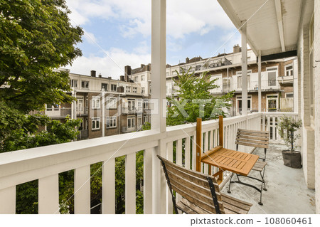 a wooden bench on a porch with trees and buildings in the background, taken from outside looking out to the street a wooden bench on a porch with trees and buildings in the background, taken from outside looking out to the street 108060461