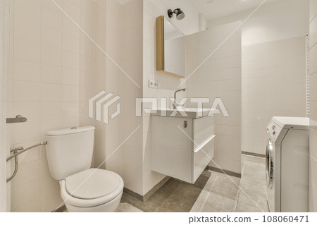 a bathroom with white tiles on the walls and toilet in the middle, there is a mirror over the sink a bathroom with white tiles on the walls and toilet in the middle, there is a mirror over the sink 108060471