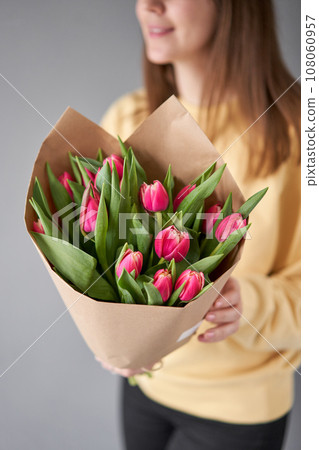 Crimson color tulips in woman hand. Spring bouquet of red tulips in hands. Bunch of fresh cut spring flowers 108060957