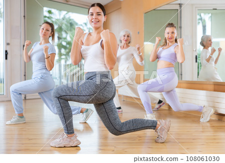 Ordinary active females exercising dance moves in modern dance studio 108061030