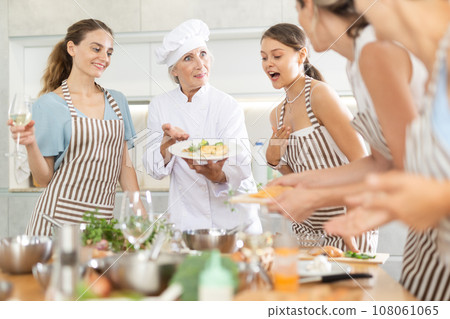 Elderly woman cook posing with prepared chicken dish 108061065