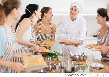 Young female cook holding cutting board with raw chicken Young female cook holding cutting board with raw chicken 108061125