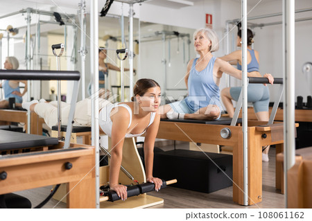 Young girl practicing pilates stretching exercises on combo chair Young girl practicing pilates stretching exercises on combo chair 108061162