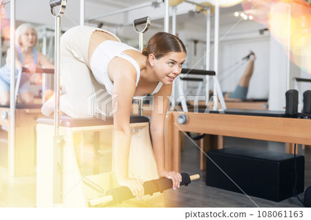 Woman pilates stretching sport in reformer bed Woman pilates stretching sport in reformer bed 108061163
