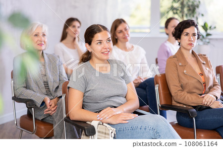 Young positive woman listening to lecture in office Young positive woman listening to lecture in office 108061164