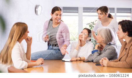Smiling young girl discussing with female volunteer group 108061224
