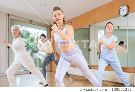 Active middle-aged woman practicing aerobic dance in training hall 108061231