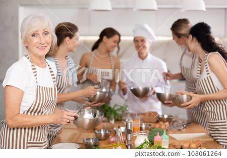Lady while studying at culinary workshop, cooks appetizing sauce, marinade, dough in bowl. Lady while studying at culinary workshop, cooks appetizing sauce, marinade, dough in bowl. 108061264