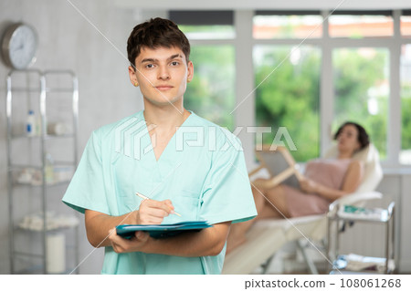Young man doctor posing in doctor's cabinet with document in hands Young man doctor posing in doctor's cabinet with document in hands 108061268