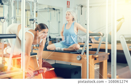 Young girl practicing pilates stretching exercises on combo chair 108061274