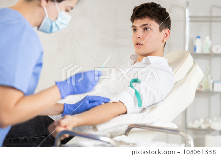 Young man having vein injection lying on clinical chair 108061338