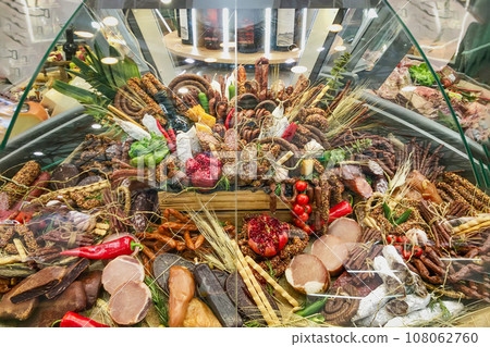 Showcase with an abundance of assortment of sausages and meat prepared products, cheese, fruit, wine 108062760