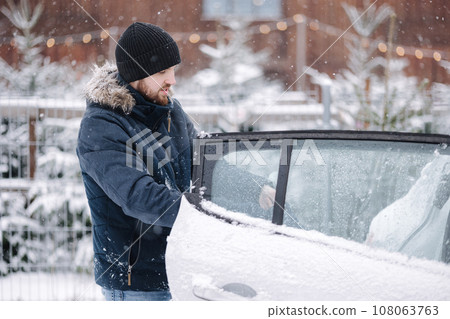Man buy fir tree and put into car. Snowy winter day. Christmas mood. Preparation for winter holidays Man buy fir tree and put into car. Snowy winter day. Christmas mood. Preparation for winter holidays 108063763
