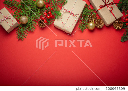 Christmas or New Year celebration red paper festive background with decoration fir tree, wrapped present boxes, cones, berries, sparkly red balls. Space for text. Christmas or New Year celebration red paper festive background with decoration fir tree, wrapped present boxes, cones, berries, sparkly red balls. Space for text. 108063809