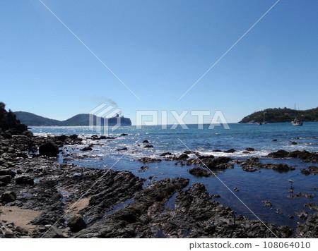 Bay of Zihuatanejo with bird playing in shore and Cruiseship in the background 108064010