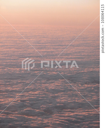 Sunset casts on tops clouds stretching into the distance Sunset casts on tops clouds stretching into the distance 108064115
