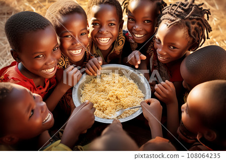Group of African children eat meager food with their hands from a large metal plate 108064235