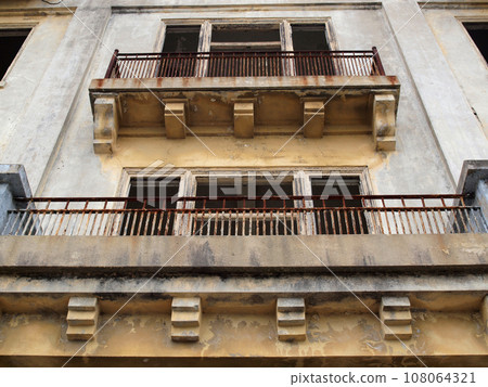 Balconies of a old worn building missing it's windows 108064321