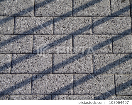 Gray Brick pathway with shadow lines crossing over it 108064407