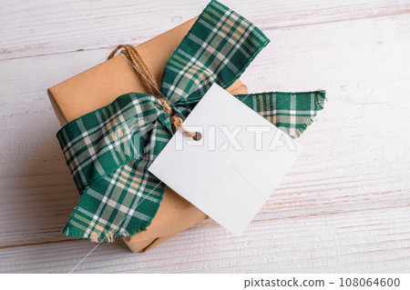 Christmas square gift tag mockup with craft wrapped gift box on a white background 108064600