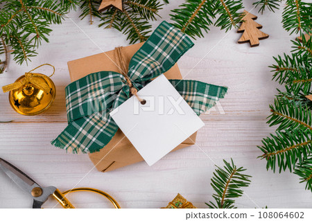Christmas square gift tag mockup with craft wrapped gift box and fir branches around 108064602
