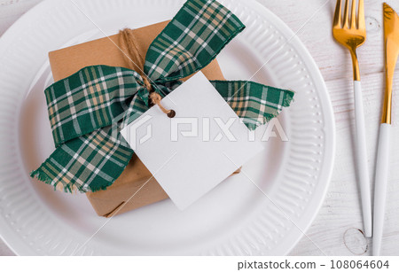 Christmas square gift tag mockup with craft wrapped gift box on a white plate, close up 108064604