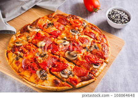 American St. Louis Style pizza with bacon, mushrooms and tomatoes on a board American St. Louis Style pizza with bacon, mushrooms and tomatoes on a board 108064648