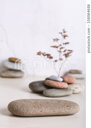A podium made of smooth sea stone and a dried flower from a pile of stones vertical view A podium made of smooth sea stone and a dried flower from a pile of stones vertical view 108064686
