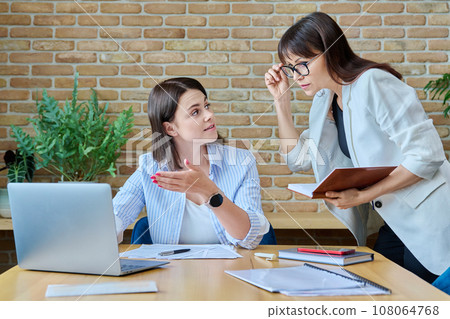 Two businesswomen talking and discussing in office Two businesswomen talking and discussing in office 108064768