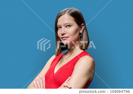 Young beautiful woman looking at camera on blue background Young beautiful woman looking at camera on blue background 108064796