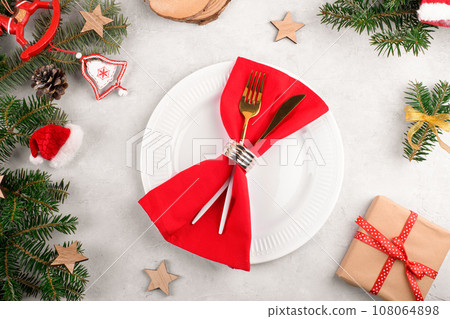 Christmas table setting with natural fir branches and gold cutlery on white plate Christmas table setting with natural fir branches and gold cutlery on white plate 108064898