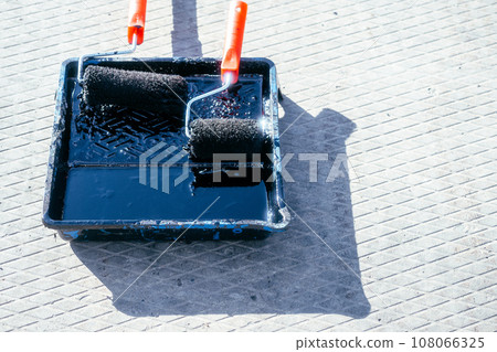 Paint roller in tray with black industrial paint or primer. Top view of paint roller with paint tray 108066325