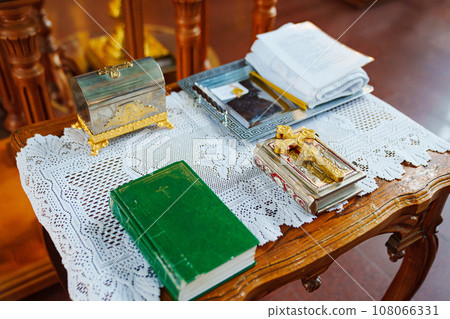 A table in the church with a bible, a Christian cross, a baptismal kit. 108066331