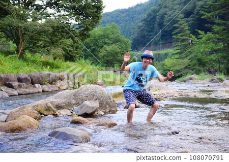 man playing in the river 108070791