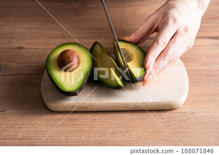hand cutting an avocado 108071846