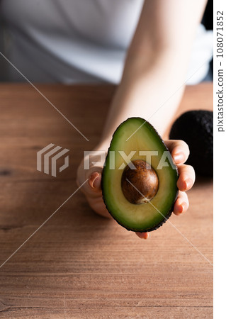 Hand holding cut avocado 108071852
