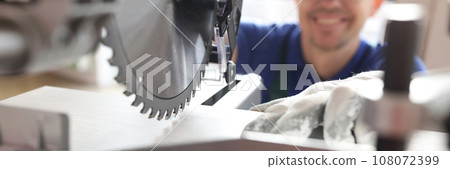 Smiling worker in cap cuts wooden board with miter saw Smiling worker in cap cuts wooden board with miter saw 108072399