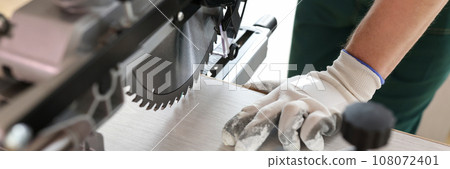 Man cuts laminate board using professional miter saw Man cuts laminate board using professional miter saw 108072401