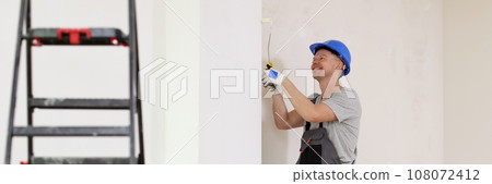 Smiling worker in uniform coveralls makes repairs in flat Smiling worker in uniform coveralls makes repairs in flat 108072412