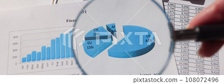 Woman looks at statistics paper through magnifier glass 108072496